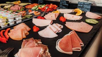 A charcuterie board with various meats, cheeses, and fruits.