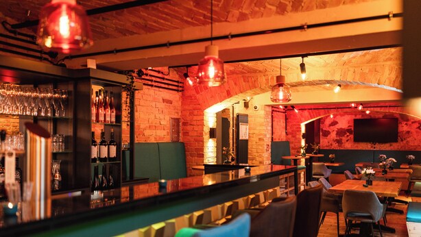 A bar area with a brick wall, hanging lights, and seating.
