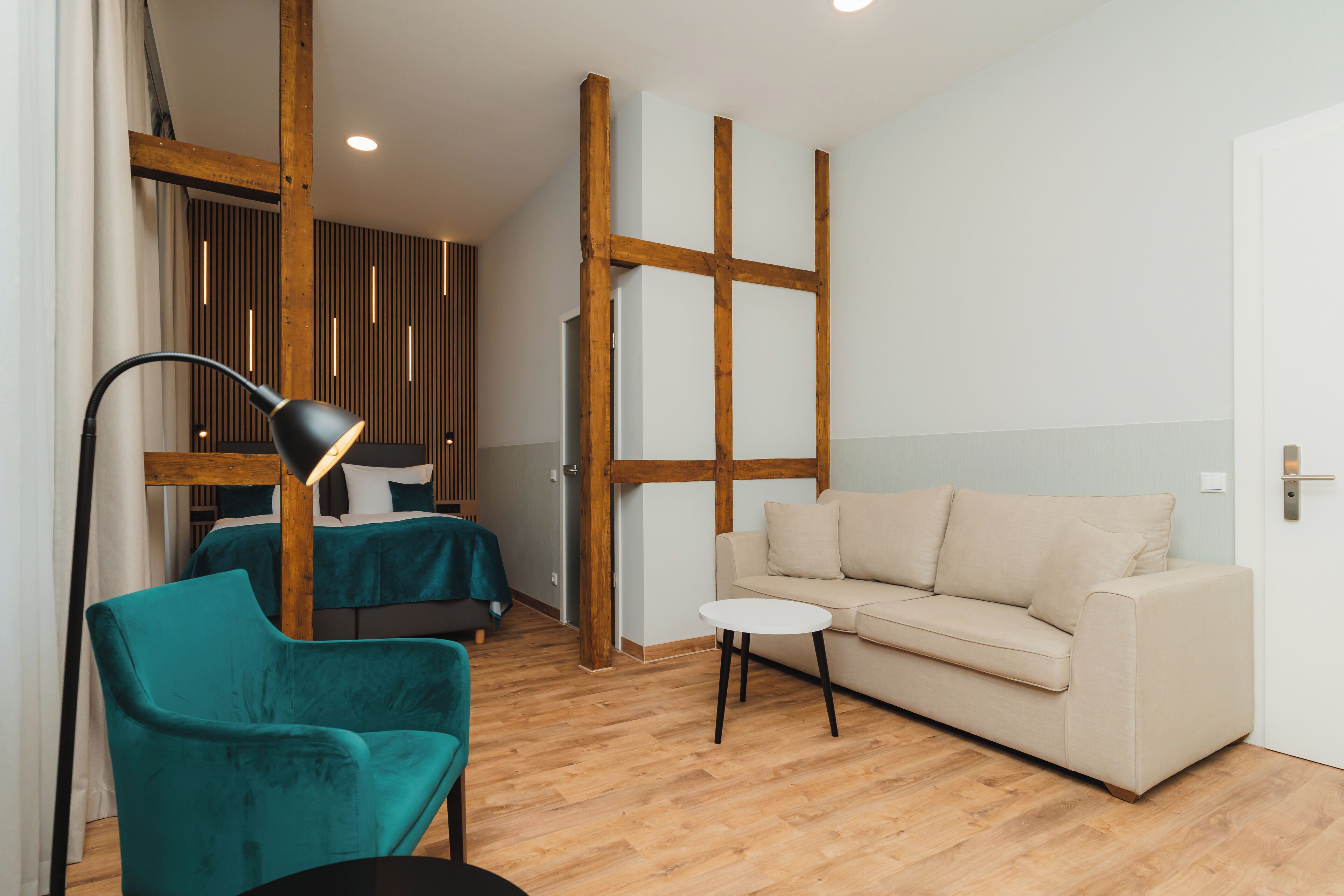 Une pièce moderne avec un plafond en bois, un fauteuil turquoise, un canapé beige et une petite table blanche.