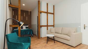 Une pièce moderne avec un plafond en bois, un fauteuil turquoise, un canapé beige et une petite table blanche.