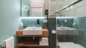 Un bagno moderno con un mobile lavabo in legno, due lavandini, un WC e un box doccia in vetro.