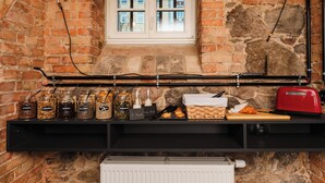 A kitchen with a brick wall, a window, and a shelf with jars and a toaster.