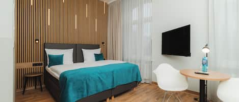 Une chambre d’hôtel moderne équipée d’un lit, d’une télévision, d’une petite table et d’une chaise.