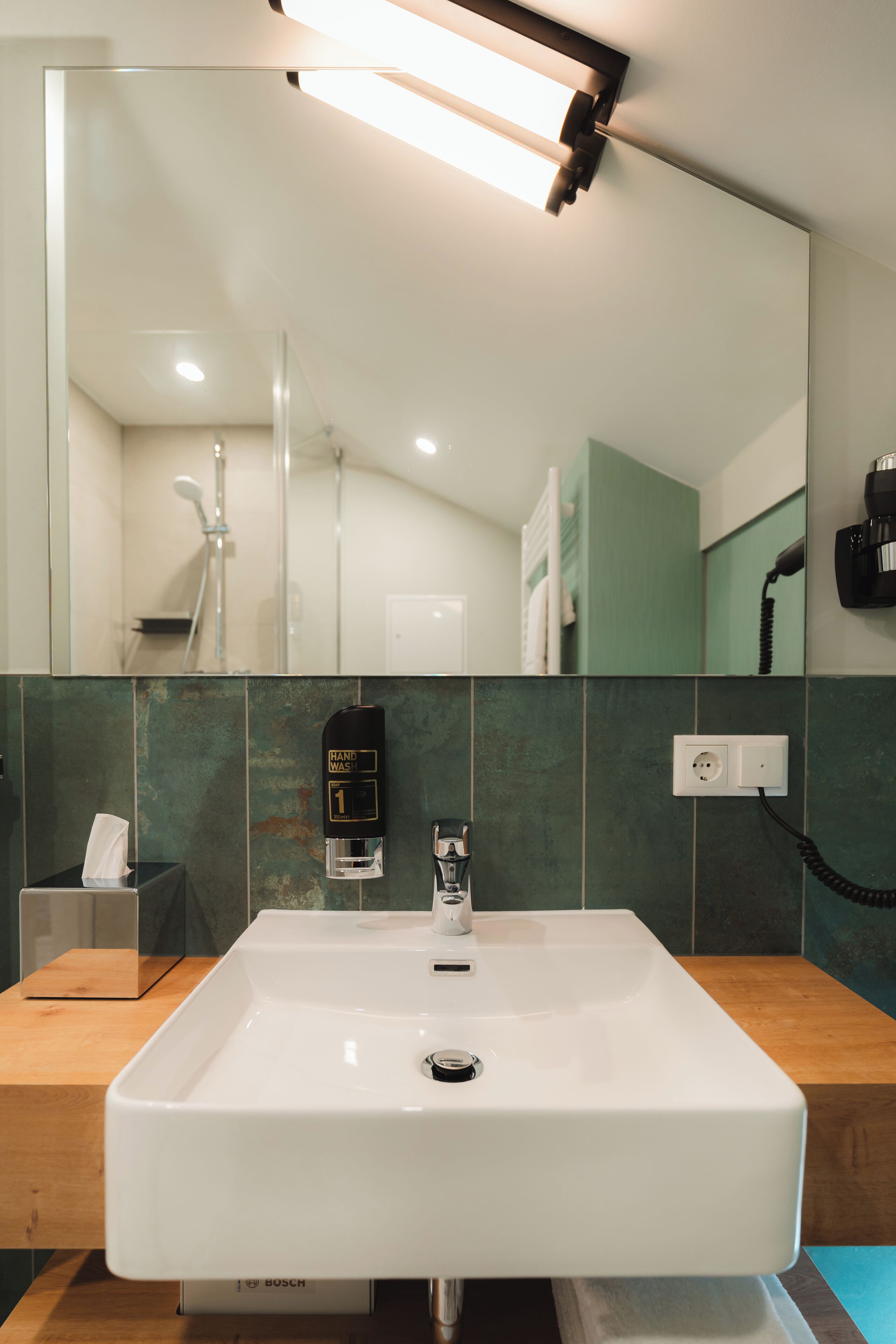 A bathroom with a white sink, a mirror, a hand dryer, and a towel rack.