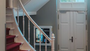 A spiral staircase with red carpeted steps and white balusters, leading to a door with a window above.