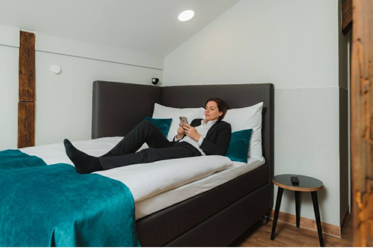 Ein modernes Schlafzimmer mit einem großen Bett, einem Nachttisch und einem kleinen Hocker.