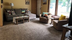 A living room with a sofa, armchair, coffee table, and a ceiling fan. - Charming 3-bedroom home within walking distance of Lambeau field! (Green Bay)