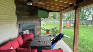 An outdoor patio with wicker furniture, a fire pit, and a view of the backyard. - Charming 3-bedroom home within walking distance of Lambeau field! (Green Bay)