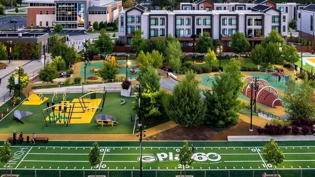 A modern building with a sports field in front. - Charming 3-bedroom home within walking distance of Lambeau field! (Green Bay)