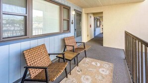 A corridor with two wooden chairs and a patterned rug, leading to a door with a light fixture. - Ocean Block-Uptown -Northside Park-Sleeps 6 (Ocean City)