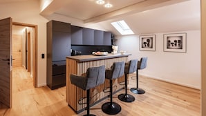 Een moderne keuken met een centraal eiland, barkrukken en een dakvenster.