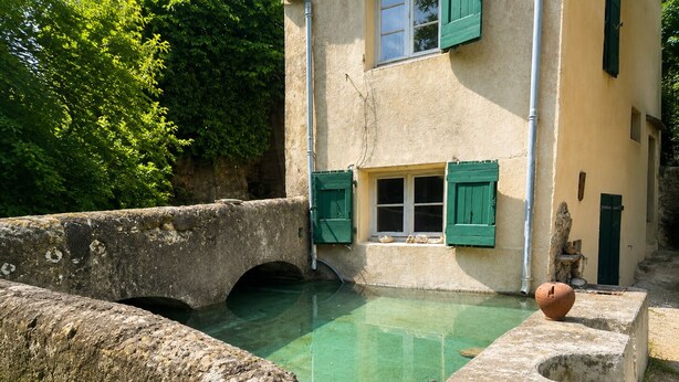 A stone bridge over a clear pool, a building with green shutters, and a rustic outdoor setting. - Cévennes-style house surrounded by nature with a swimming pond (Monoblet)
