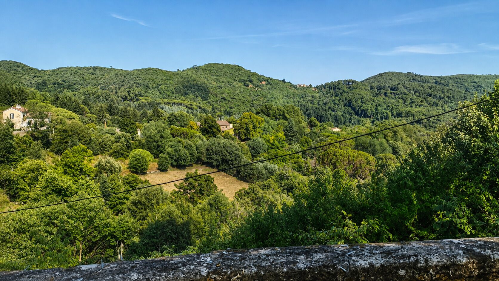 Un paysage montagneux, caractérisé par une végétation luxuriante et quelques bâtiments visibles au loin.