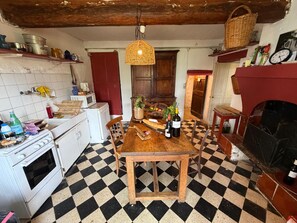 Una cocina con piso a cuadros, una mesa de madera y diferentes electrodomésticos.
