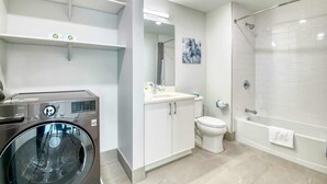 Une salle de bain moderne équipée d’un lave-linge, de toilettes, d’un lavabo et d’une baignoire.