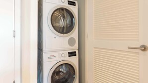 A stacked washer and dryer unit in a room with a white door and a white wall. - Private Apt Downtown Walk to Harbor (Boston)