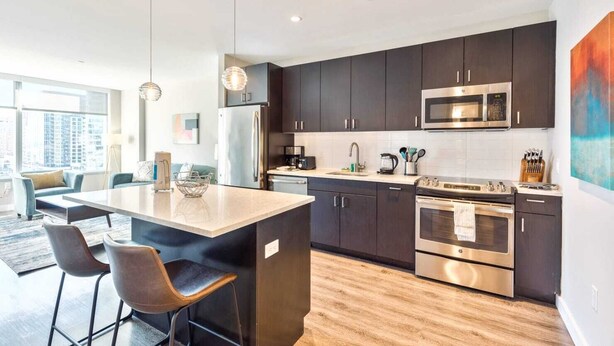 A modern kitchen with dark cabinets, stainless steel appliances, and a central island with bar stools. - Private Apt Downtown Walk to Harbor (Boston)