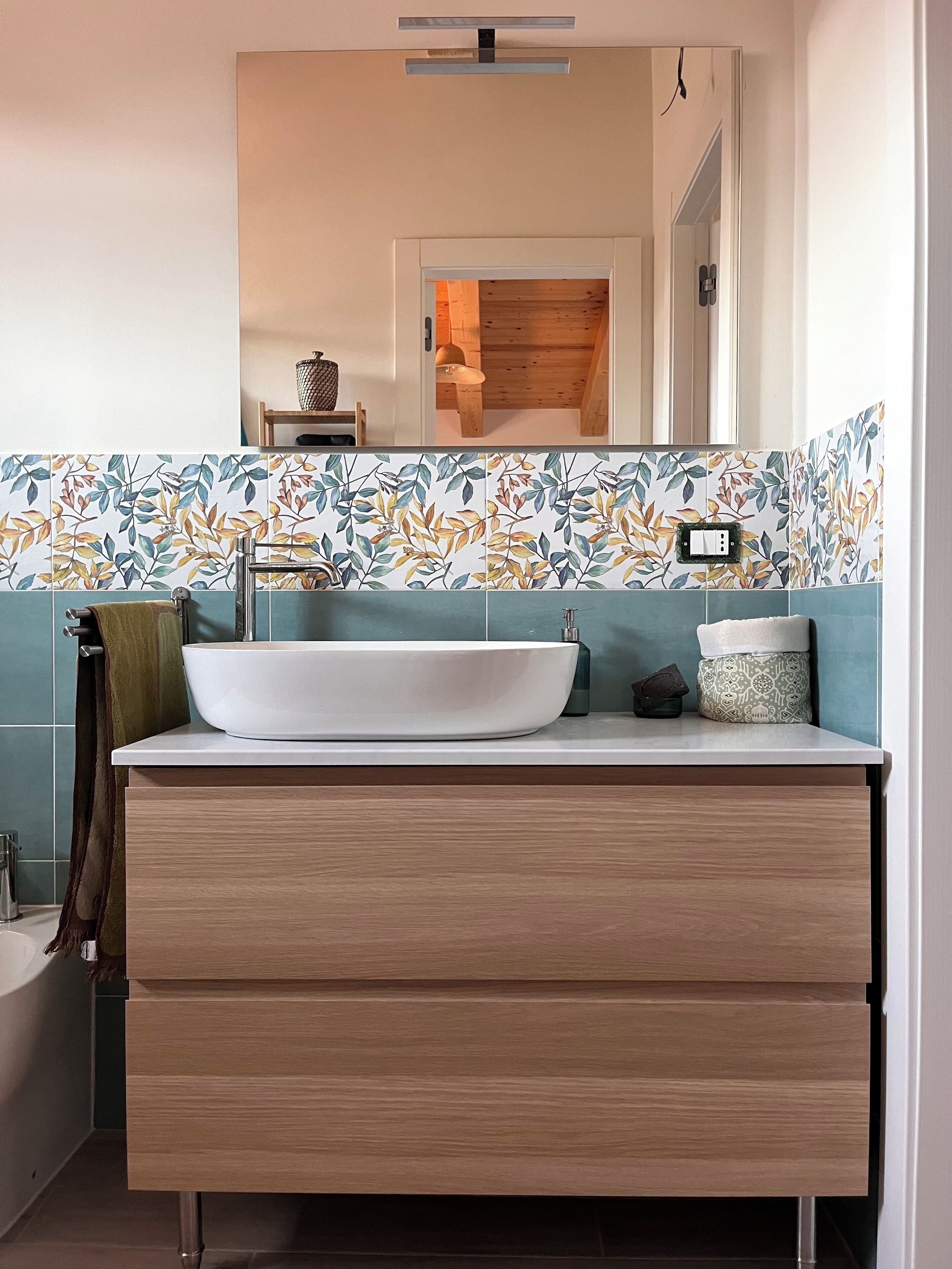 A bathroom with a white vessel sink, wooden vanity, and a mirror above.