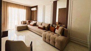A modern living room with a sectional sofa, a glass coffee table, and a large mirror. - Appartement à Louer Garden Paradise Bouznika (bouznika)