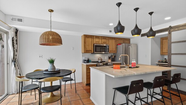 Une cuisine moderne dotée d’un îlot central, de meubles en bois et de luminaires suspendus.