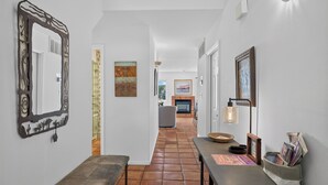 Un couloir avec un banc, une table avec des magazines, un miroir fixé au mur et une cheminée en arrière-plan.