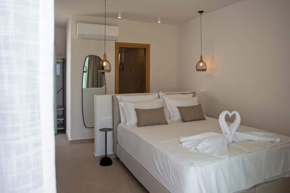 A modern bedroom with a large bed, two bedside tables, a mirror, and a ceiling light.