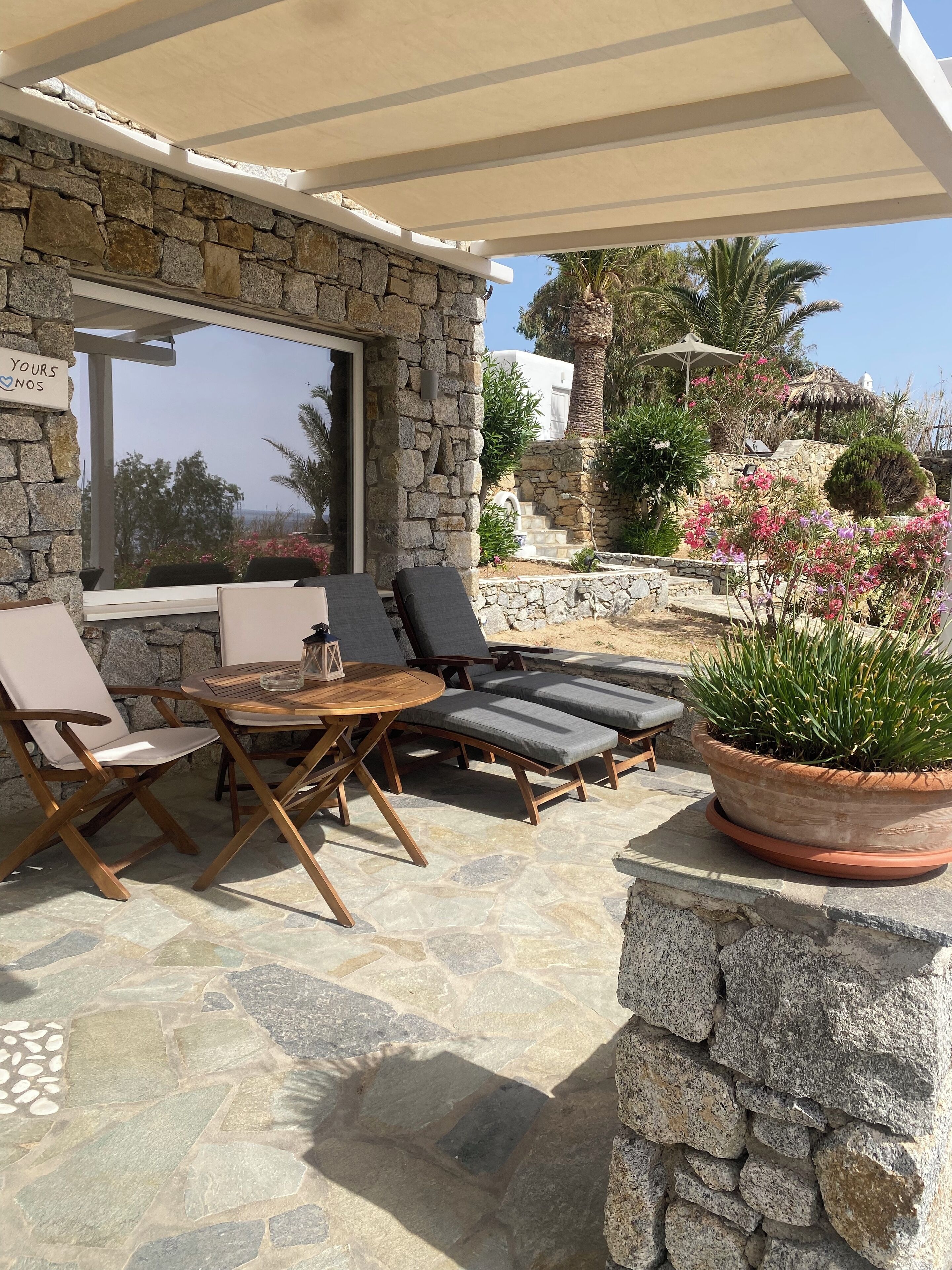 A stone patio with a table and chairs, a stone wall, and a potted plant.
