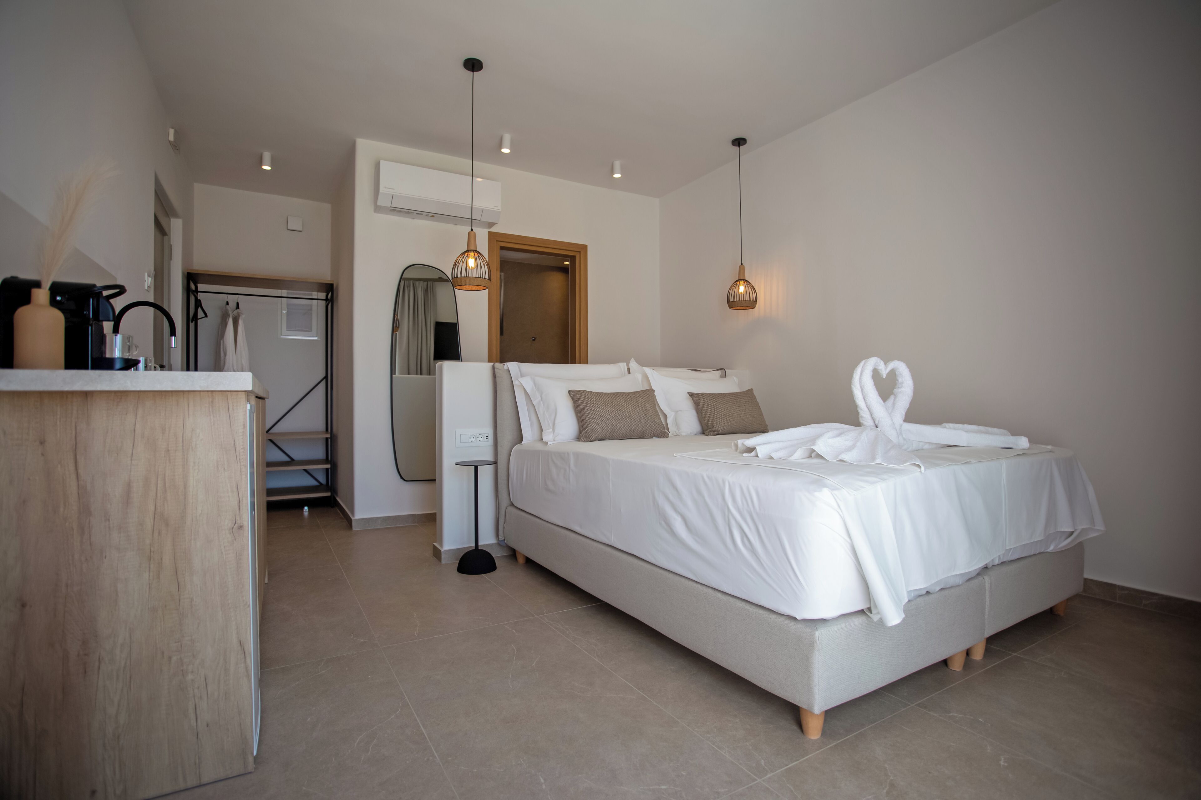 A modern bedroom with a large bed, bedside tables, a mirror, and a wardrobe.