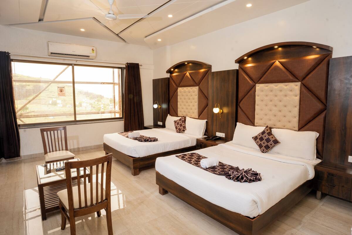 Quarto de hotel com duas camas, uma mesa de jantar e cadeiras.