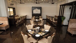 Un espace repas avec une grande table ronde, dressée pour six personnes, entourée de six chaises.