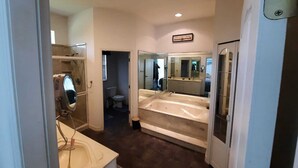 Un baño moderno con una bañera grande, zona de ducha separada y tocador con espejo.