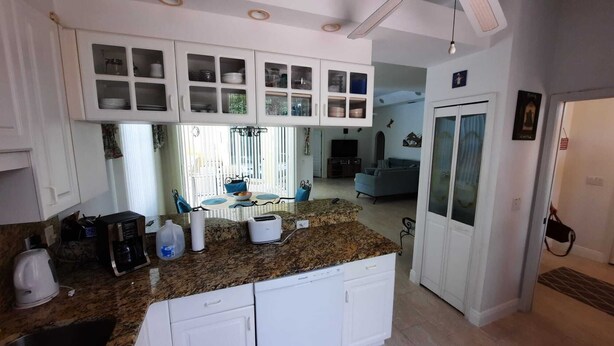 Una cocina moderna con armarios blancos, encimeras de granito y lavavajillas integrado.