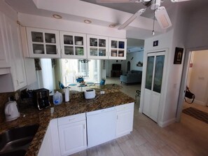A modern kitchen with white cabinets, granite countertops, and a built-in dishwasher. - Wunderschöne Villa auf Einem Über 6.000 qm Grundstück (Lehigh Acres)