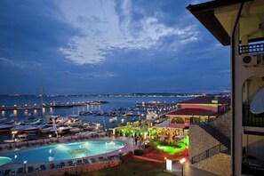 A marina at dusk with boats docked, a swimming pool, and a restaurant with outdoor seating. - LAZUR 1-5 Apart Complex (Sveti Vlas)