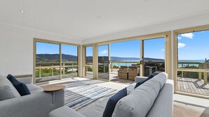 Un amplio salón con ventanas grandes, un sofá y vistas al océano.