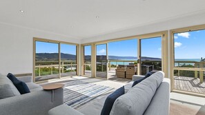 A spacious living area with large windows, a sofa, and a view of the ocean. - Majestic Views (Marengo)