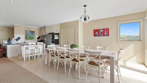 A spacious dining area with a large table and chairs, a kitchen in the background, and a painting on the wall. - Majestic Views (Marengo)