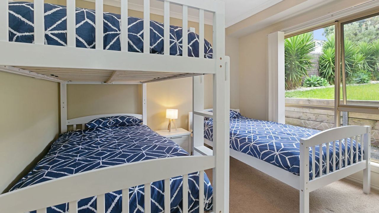 A bunk bed room with a window view of a garden.