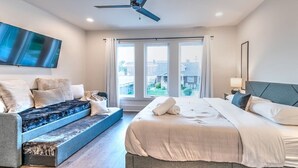 Un dormitorio con una cama, un sofá cama, un ventilador de techo y un ventanal grande.