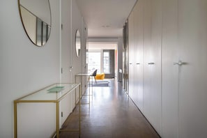 A hallway with a glass table, a chair, and a mirror on the wall.