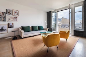 A modern living room with a sofa, two armchairs, a coffee table, and artwork on the walls. - Elegant Paris Apartment on Avenue Montaigne (Paris)