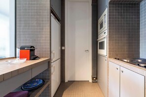 A kitchen with a microwave, oven, and a sink.