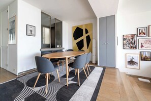 A modern dining area with a round table, chairs, and a large abstract painting on the wall.