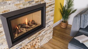 A fireplace with a stone facade, a grey sofa, and a potted plant. - Beechwood Brook, 3 bed, 3 bath, parking, Bowness (Bowness-on-Windermere)