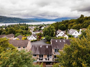 Et boligområde med huse, en sø og bjerge i baggrunden.