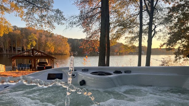 A hot tub with a view of a lake and autumn trees.