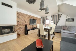 A modern living room with a fireplace, a dining area, and a grey sofa. - Two-level Apartment for 6 | Balcony | Close to Aquapark (Wrocław)
