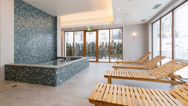 A spa area with a mosaic wall, a hot tub, and wooden loungers. - Stylish Apartment in Zakopane | Spa Access and Parking (Zakopane)