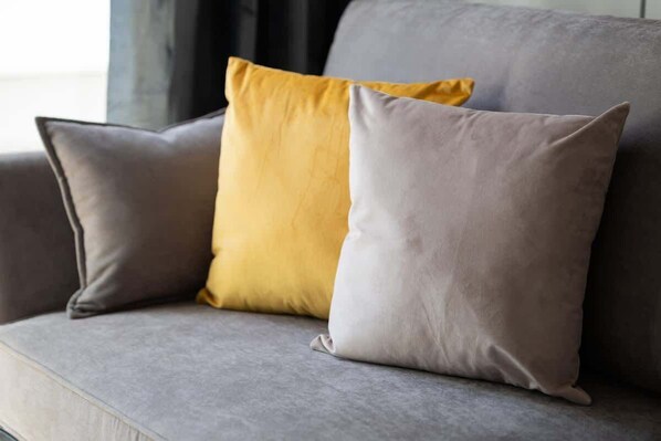 Un sofá gris con dos cojines, uno amarillo y otro gris.