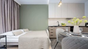 A modern bedroom with a bed, bedside table, and a dining area with a table set for two. - Practical Studio in Mokotow | Parking | Desk (Warszawa)